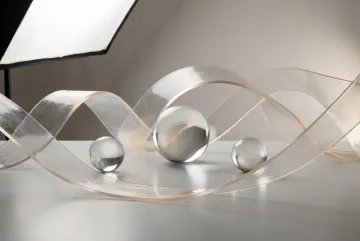 Translucent resin ribbons curve around clear glass spheres on a reflective studio surface with soft amber highlights and controlled shadows.