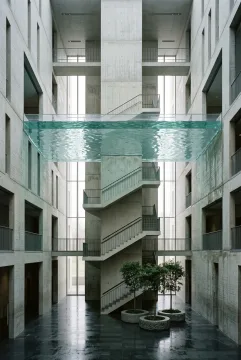 Surreal concrete archive atrium with a monumental staircase rising through a suspended indoor tide above a reflective stone floor.